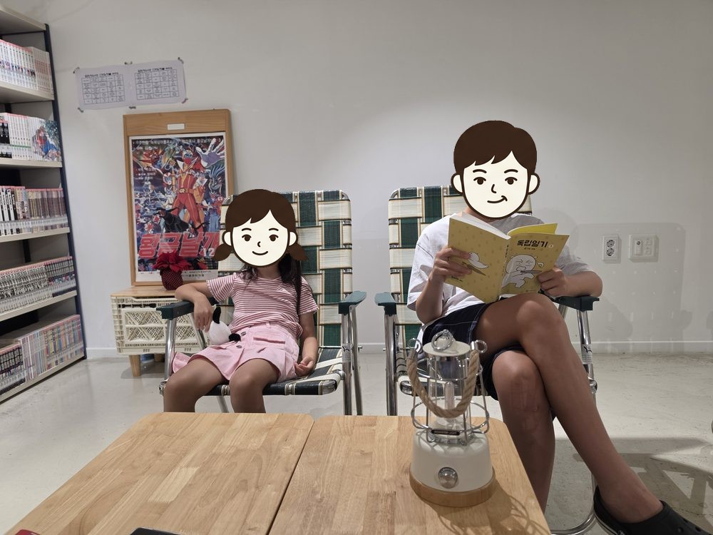 책방 캠핑 의자에 앉은 모아와 책 읽는 모험
