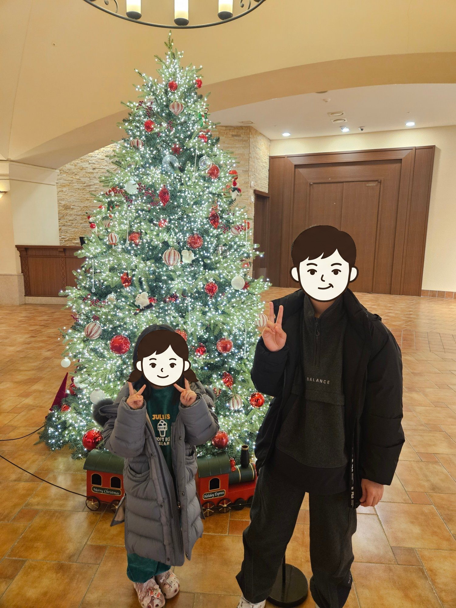 리조트 로비 크리스마스 트리 앞에서 브이를 하는 둘째와 첫째
