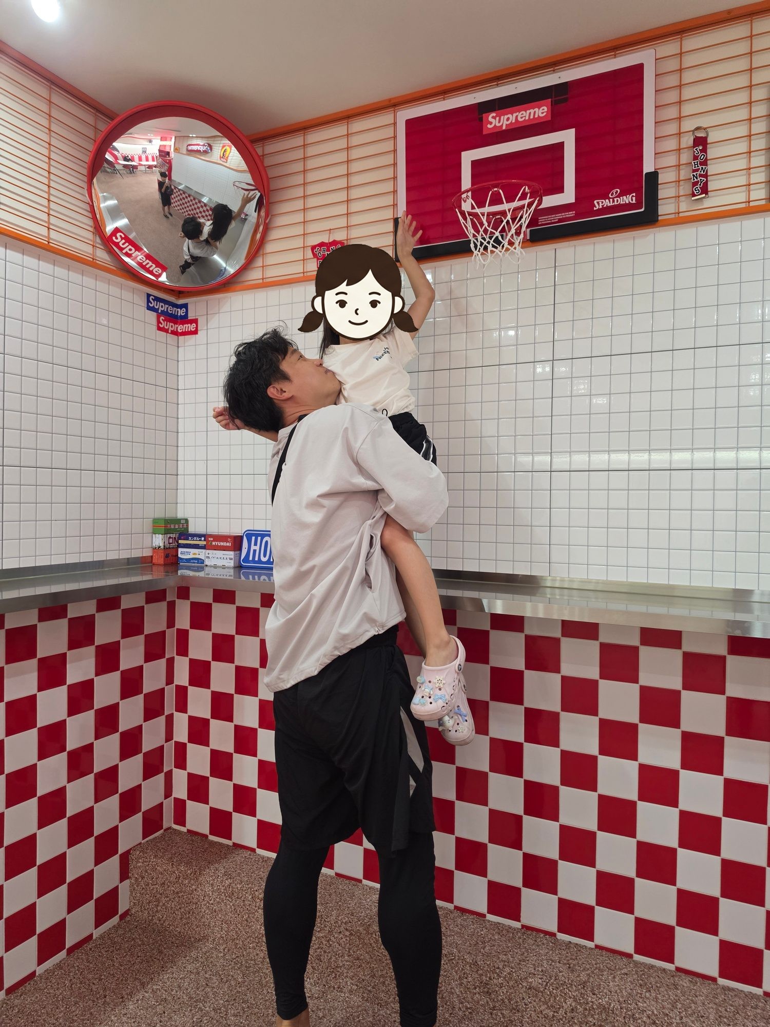 아빠가 둘째를 안아 올려 농구 골대에 손이 닿게 한 모습