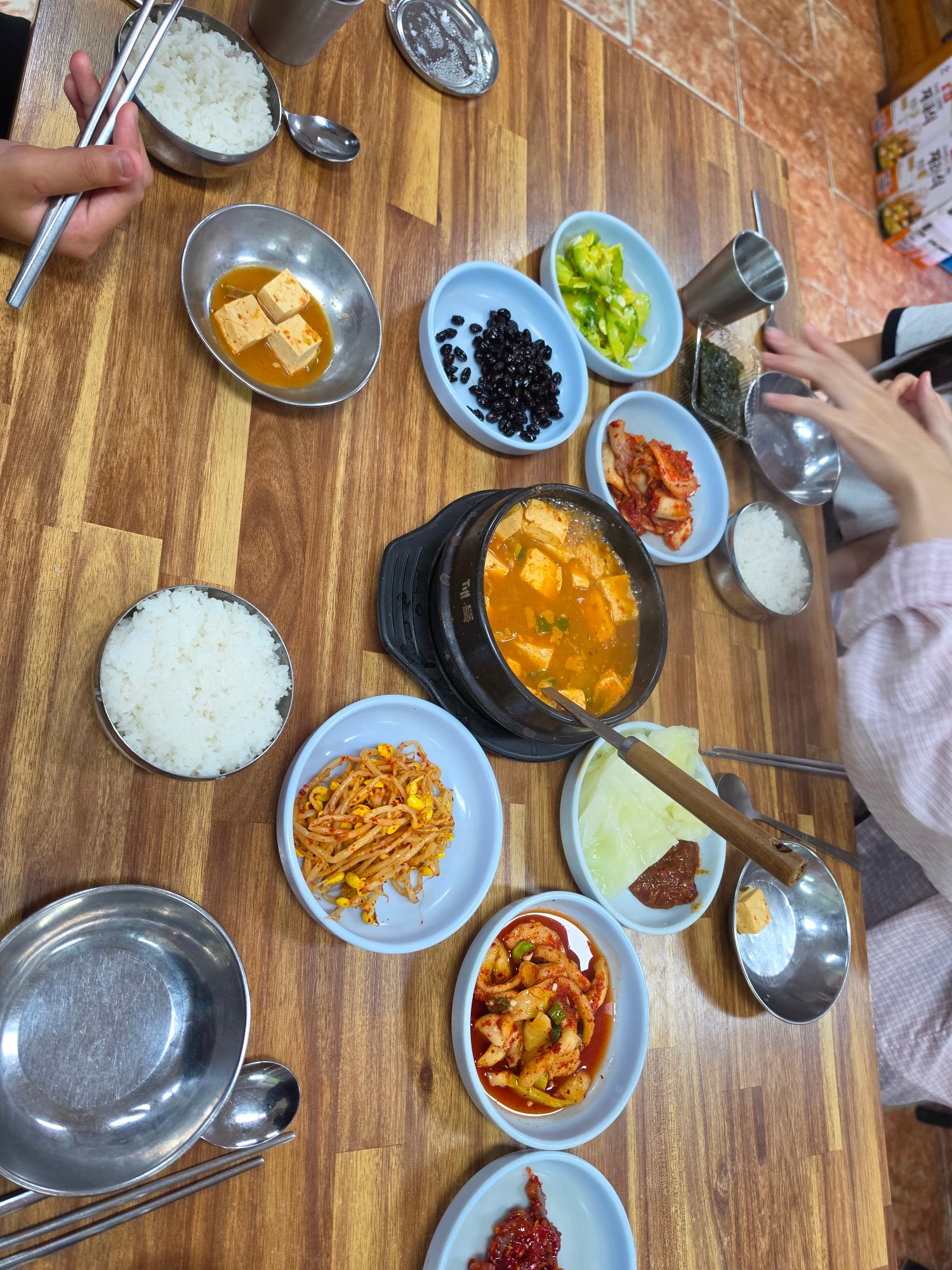 초원식당 상에 가득 차려진 반찬과 뚝배기, 밥그릇들